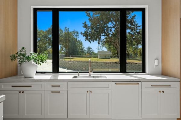 Kitchen sink and cabinets with a large window view representing residential drain cleaning